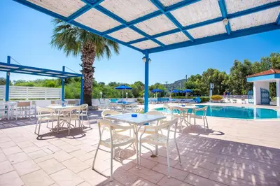 a patio with tables and chairs next to a pool at Muses Hotel in Faliraki