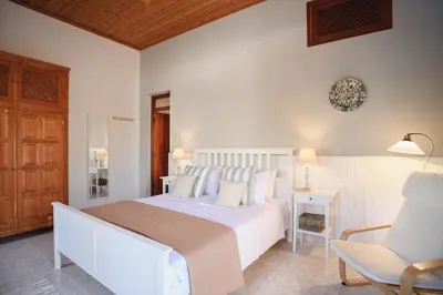 a bedroom with a large white bed and a chair at Thea Villas and Suite in Líndos