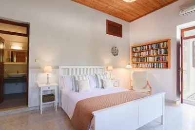 a bedroom with a white bed and a book shelf at Thea Villas and Suite in Líndos