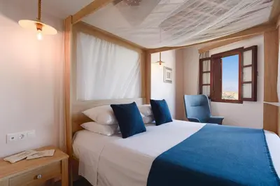 a bedroom with a bed and a blue chair at Thea Villas and Suite in Líndos