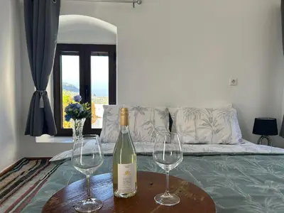 a bottle of wine and two wine glasses on a table at New Lindos Studio 45 renovated in Líndos