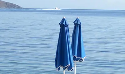 two blue umbrellas sitting on top of the ocean at Kleopatra's Rooms in Livadia