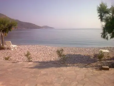 a beach with two chairs and the water at Kleopatra's Rooms in Livadia