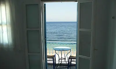 a room with a view of the ocean from a balcony at Kleopatra's Rooms in Livadia