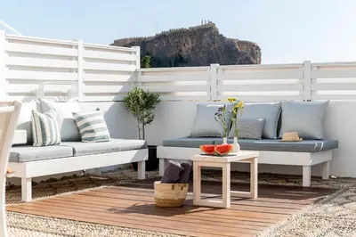 a patio with two benches and a table with fruit on it at Traditional Lindian Suites in Líndos