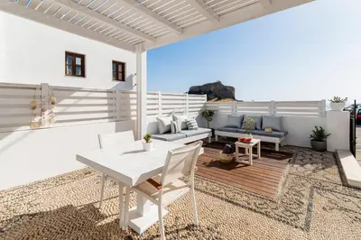 a white patio with a white table and chairs at Traditional Lindian Suites in Líndos