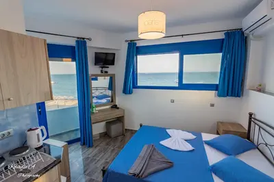 a bedroom with a blue bed and a view of the ocean at Riva Del Mare in Archangelos