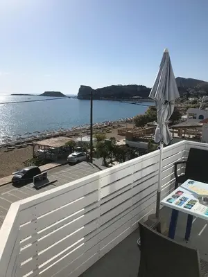 a balcony with an umbrella and a view of the ocean at Riva Del Mare in Archangelos