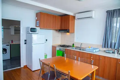 a kitchen with a wooden table and a white refrigerator at Riva Del Mare in Archangelos