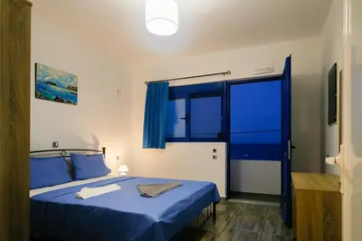 a bedroom with a blue bed and a window at Riva Del Mare in Archangelos