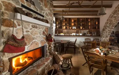 a fireplace in a room with a table and a dining room at Limeri Traditional Guest House in Monólithos