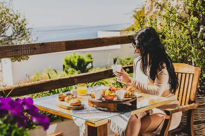 a woman sitting at a table with a plate of food at Limeri Traditional Guest House in Monólithos