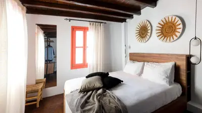 a bedroom with a bed with white sheets and a window at Blue Jasmine Suites in Rhodes Town