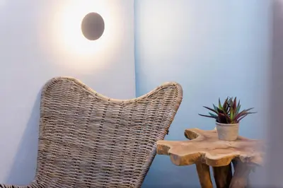 a wicker chair and a table with a plant on it at Blue Jasmine Suites in Rhodes Town
