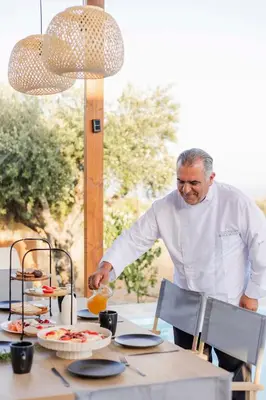 a man standing at a table preparing food at Villa Tranquila Rhodes in Psinthos