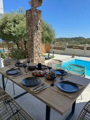 a wooden table with plates and wine glasses on it at Villa Tranquila Rhodes in Psinthos