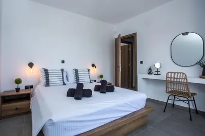 a bedroom with a white bed with a chair and a mirror at Villa Tranquila Rhodes in Psinthos