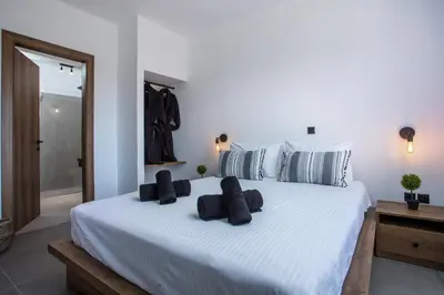 a bedroom with a large white bed with black pillows at Villa Tranquila Rhodes in Psinthos