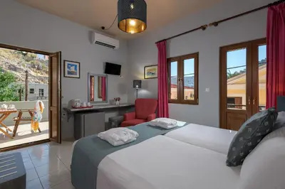a bedroom with two beds and a desk and a chair at Grace Hotel & Studios in Symi