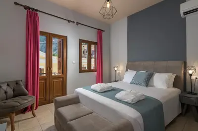 a bedroom with a bed and a chair and a window at Grace Hotel & Studios in Symi