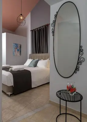 a bedroom with a bed and a mirror on the wall at Grace Hotel & Studios in Symi