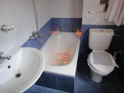 a bathroom with a tub and a toilet and a sink at Captain's Suites in Symi