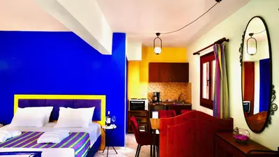 a blue room with a bed and a kitchen at Captain's Suites in Symi
