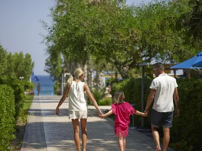 a man and a girl walking down a sidewalk holding hands at Esperides Beach Resort in Faliraki