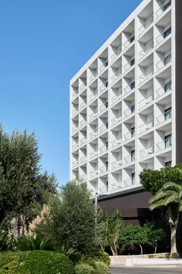 a large white building with trees in front of it at Esperides Beach Resort in Faliraki