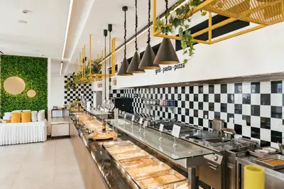 a restaurant kitchen with a long counter with food at Esperides Beach Resort in Faliraki
