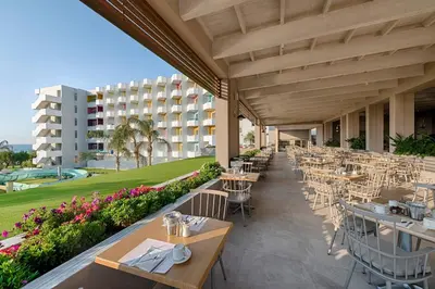 a restaurant with tables and chairs and a building at Esperides Beach Resort in Faliraki