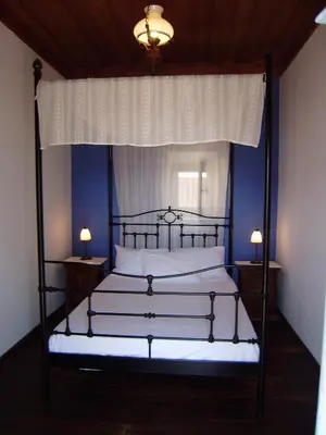a bedroom with a canopy bed with white sheets and two lamps at Villa Katingo in Halki