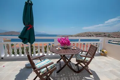 a table and two chairs and an umbrella on a balcony at Filoxenia Apartments in Halki