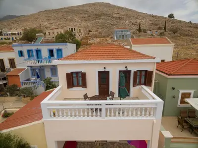a white house with a balcony in a village at Filoxenia Apartments in Halki