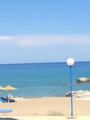 a beach with chairs and an umbrella and the ocean at Kima Stegna sea view in Archangelos