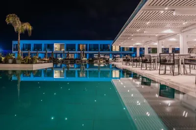 a swimming pool with tables and chairs next to a building at Gennadi Grand Resort - Premium All Inclusive in Gennadi