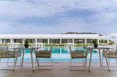 a patio with a table and chairs next to a pool at Gennadi Grand Resort - Premium All Inclusive in Gennadi