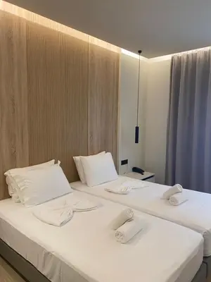 two beds in a room with white towels on them at Barbie Hotel Apartments in Ialyssos