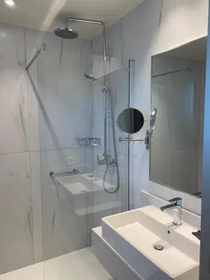 a bathroom with a shower and a sink and a mirror at Barbie Hotel Apartments in Ialyssos