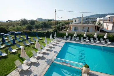 a swimming pool with lounge chairs and umbrellas at Barbie Hotel Apartments in Ialyssos