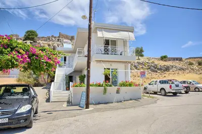a white house with cars parked in a parking lot at Haraki View in Haraki