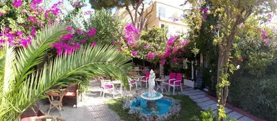 a garden with tables and chairs and purple flowers at Hotel Kalithea in Kallithea Rhodes