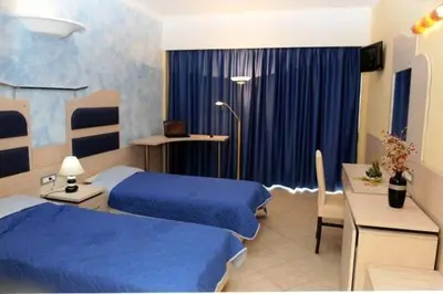 a hotel room with two beds and a table and a desk at Hotel Kalithea in Kallithea Rhodes