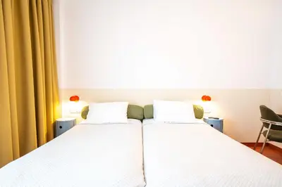 two beds in a hotel room with white sheets at Orion Hotel in Faliraki
