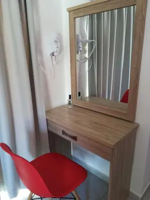 a red chair sitting next to a desk with a mirror at Family House Faliraki Studios Apartments in Faliraki