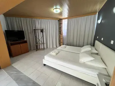 a bedroom with a large white bed and a television at Family House Faliraki Studios Apartments in Faliraki