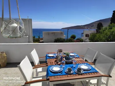 a table and chairs on a balcony with the ocean at Estella’s House in Livadia