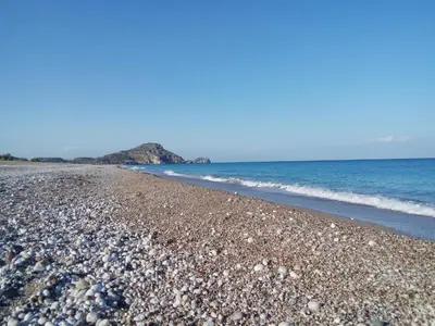 a beach covered in rocks and the ocean at Levande Studio with private parking in Afantou
