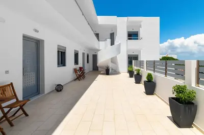 a balcony of a white building with chairs and plants at Ble Azzure in Gennadi