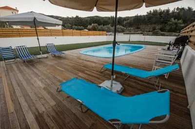a patio with two blue chairs and an umbrella at Butterfly Estates Maritsa Rhodes in Pastida
